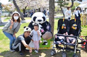 パンダのぬいぐるみと記念撮影をする家族