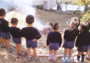 園児たちが、いもが焼けるところを見ている写真です。