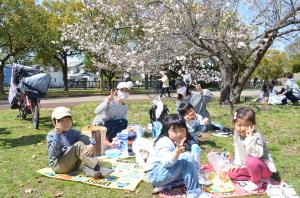 桜の木の下でピクニックをする子ども4人と大人2人
