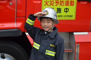 消防車の前で防火服を着る男の子