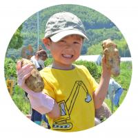 収穫したジャガイモを持つ笑顔の男の子