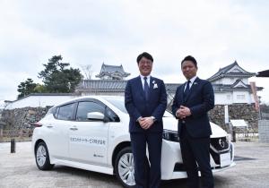 リユース車両と岸和田城をバックに佐藤社長（左）と永野市長（右）