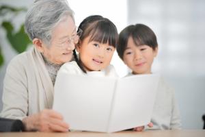 おばあちゃんが孫に読み聞かせをしている写真