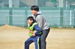 学習支援員の桐谷敦也さんが体育の授業で子どもたちとサッカーをする様子